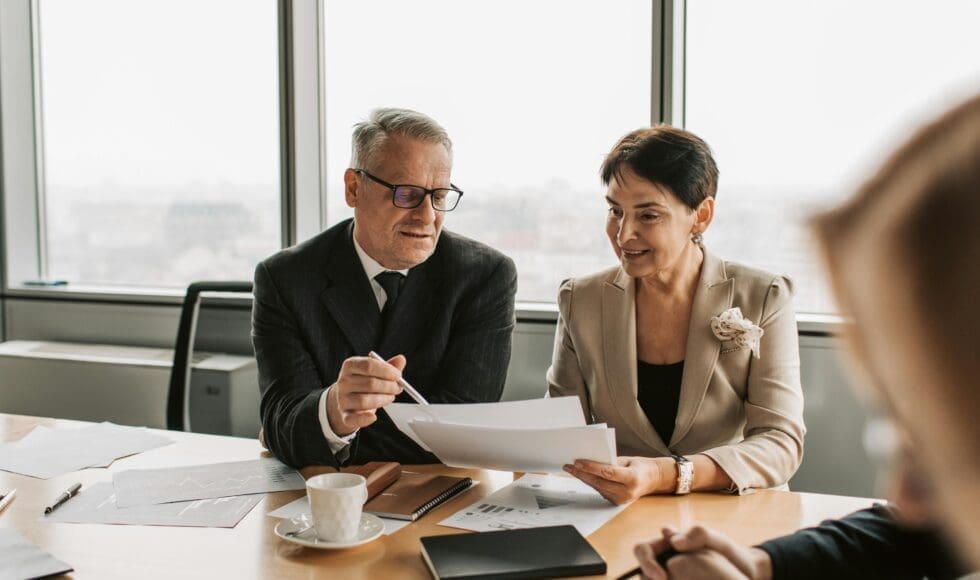 Business professionals discussing documents in a meeting room.